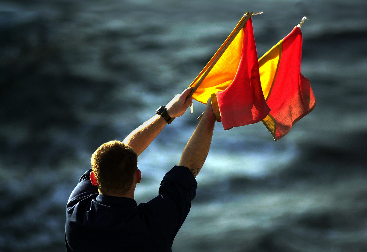 marinaio segna con bandiere giallo rosso